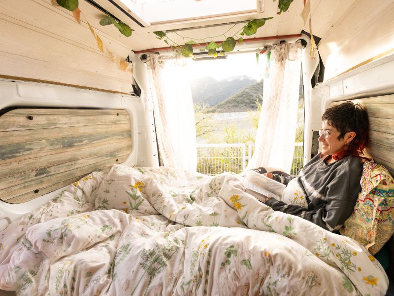 Une femme lisant dans un van aménagé.